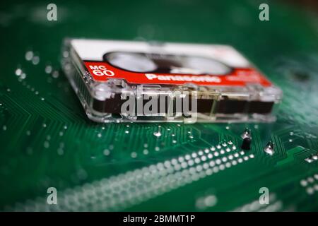 Viersen, Germany - May 9. 2020: Isolated old recorder tape on green computer circuit board (focus on tape) Stock Photo
