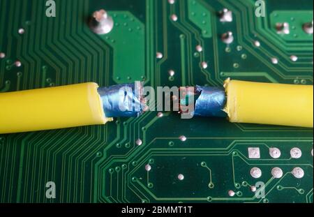 Interrupted internet connection concept: isolated broken yellow electric cable on green circuit board Stock Photo
