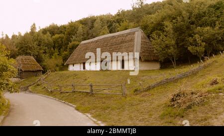 Large thatched house and asphalt road near it. Stock Photo