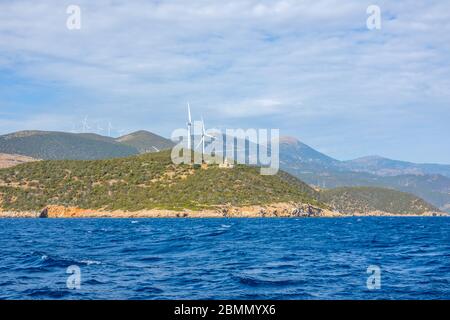 Greece. Hilly coast of the Gulf of Corinth in sunny day. Old lighthouse building and many wind farms Stock Photo