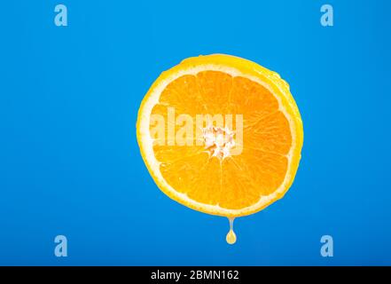 Fresh orange. Fruits on a blue background. Cut orange. Fruit juice drops. Vegetarian dish. Fresh citruses. Drops of water on the skin. Dripping fruit Stock Photo