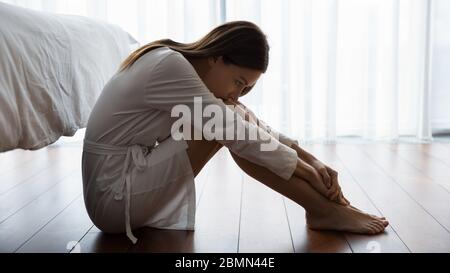 Sad woman sitting on floor looking unhappy suffers from loneliness Stock Photo