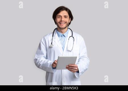 Cheerful doctor using digital tablet in hands Stock Photo