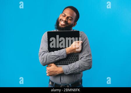 Smiling african american guy holding personal computer Stock Photo