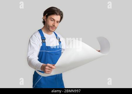 Professional Foreman Wearing Uniform Checking Construction Draft Over Light Studio Background Stock Photo