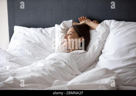 Woman wake up lying in bed dreaming enjoy new day Stock Photo