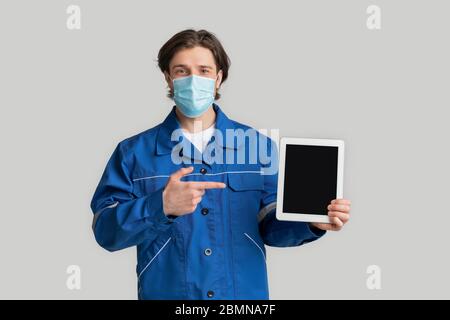 Construction Workers Recruitment During Coronavirus. Laborer In Mask Pointing At Digital Tablet Stock Photo