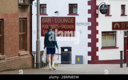 Magheralin, County Armagh, Northern Ireland. 10 May 2020. UK weather - cooler and breezy in the north-easterly wind but a very pelasant spring day nonetheless. Community spirit in the village as young man in shorts combines his daily exercise with letter-picking in the village. Credit: CAZIMB/Alamy Live News. Stock Photo