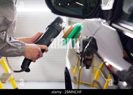 Man using polisher to polish black car body in the workshop Stock Photo