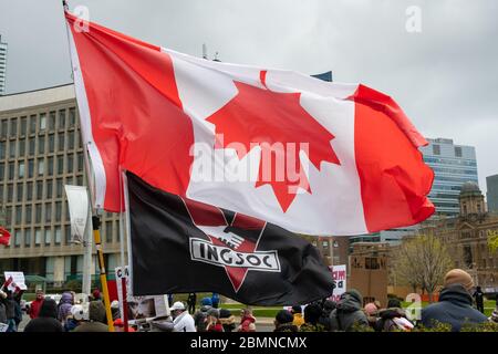 An INGSOC flag from George Orwell's 1984 flies alongside an upside-down Canada Flag outside Queen's Park at a protest against the COVID-19 Shutdown.