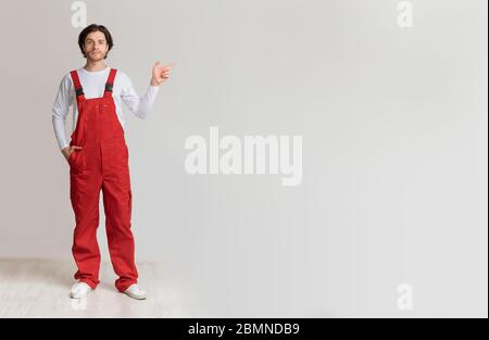Confident young laborer in work uniform pointing aside at copy space Stock Photo