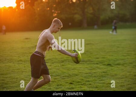 A muscly teenager plays rugby at sundown in a London park Stock Photo