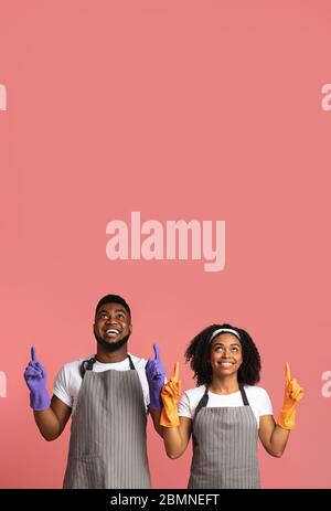 Cleaning Service Offer. Joyful Black Couple In Rubber Gloves Pointing Upwards Stock Photo