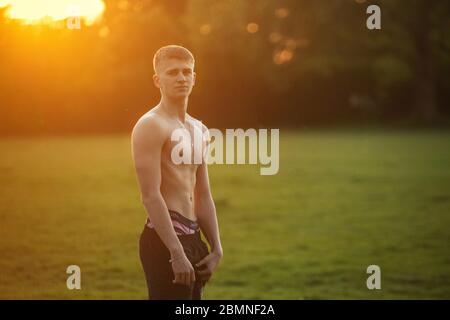 A muscly teenager plays rugby at sundown in a London park Stock Photo