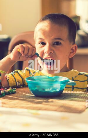 The boy 4 years eats porridge. Children's table. The concept of the child's independence. the boy is breakfasting with an appetite on the kitchen Stock Photo