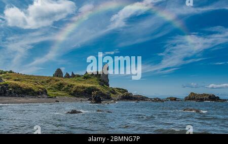 Dunure Rugged sea defences, its ancient castle ruins and a rainbow arching over the old ruins Stock Photo