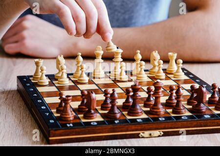 High-resolution photos for printing. A chessboard with the pieces arranged. A chess player takes a pawn in his hand and makes the first move in a ches Stock Photo