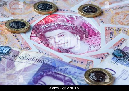 Fifty Pound note surrounded by Ten and Twenty Pound Notes with some one pound coins Stock Photo