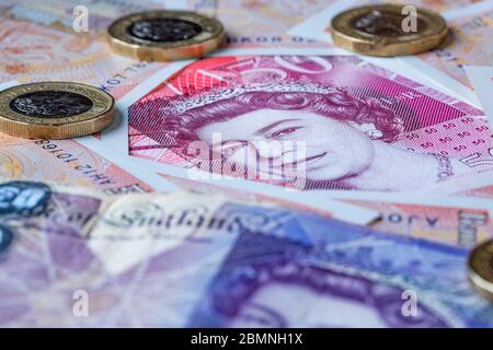 Fifty Pound note surrounded by Ten and Twenty Pound Notes with some one pound coins Stock Photo