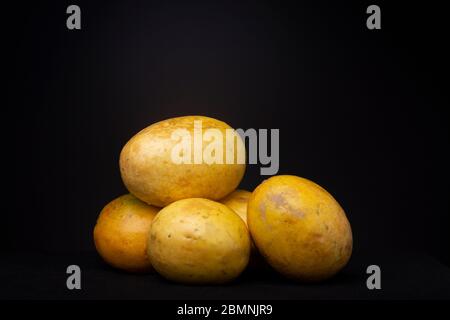 Ripe vibrant yellow Passion fruit fruits against a dark grey background. Studio low key food still life.