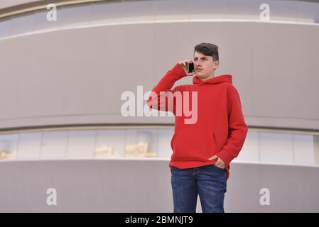 worried young man talking on his smarthphone sitting on the sidewalk Stock Photo