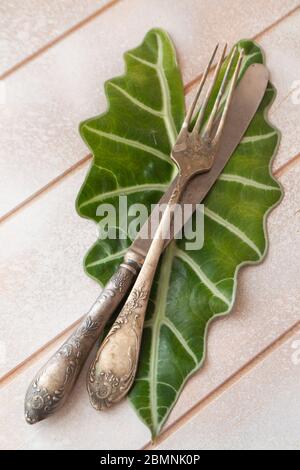 Rustic table place setting, top view, knife and fork on a leaf, vertical image Stock Photo