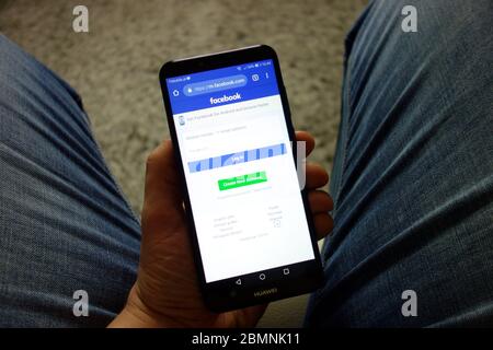 Man holding Huawei smartphone with Facebook website displayed. Social media using concept Stock Photo