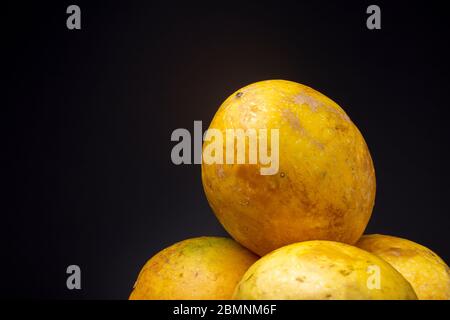 Ripe vibrant yellow Passion fruit fruits against a dark grey background. Studio low key food still life.