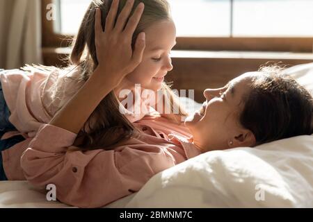 Happy mother and adorable little daughter lying in bed Stock Photo