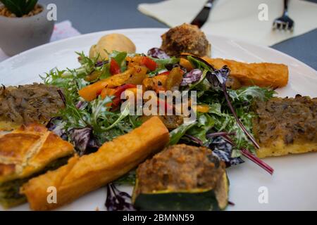 Traditional Niçoise food selection, mix of different traditional dishes served on a white plate at a restaurant in Monte Carlo Stock Photo