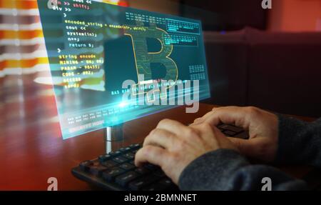 Hacker typing on the keyboard and Bitcoin mining on hologram screen on desk. Digital crypto currency, cyber money and digital banking concept. Stock Photo