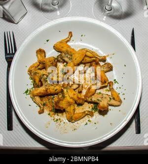 Grenouille: The French Delicacy of Frog Legs being served in a white plate at a traditional cuisine restaurant in Nice, France. Stock Photo