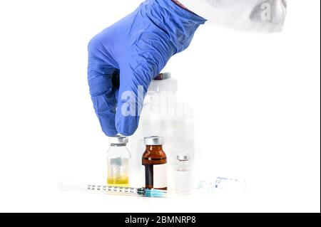 Pharmaceutical Scientist picking up a vaccine vial. Coronavirus vaccine research. Medicine vials in white background . Stock Photo
