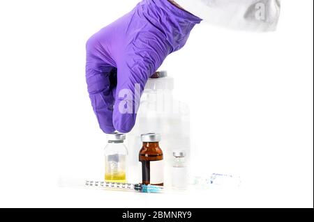 Pharmaceutical Scientist picking up a vaccine vial. Coronavirus vaccine research. Medicine vials in white background . Stock Photo