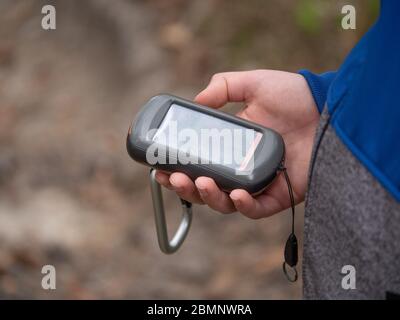 Hiker searching cache using global positioning device. Boy looking on the gps navigator in forest Stock Photo