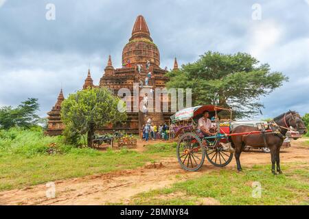 Bagan Myanmar October 29 2013; Tourists climbing the steps up a temple of stupa while horse and cart transport wait at bottom.
