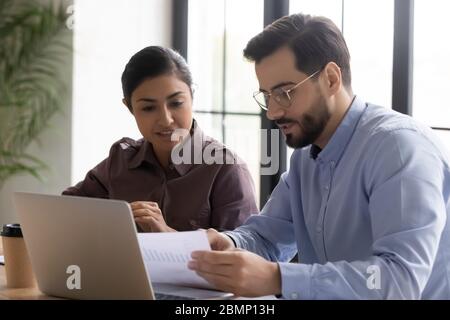 Diverse smiling businessman and businesswoman reading finance report. Stock Photo