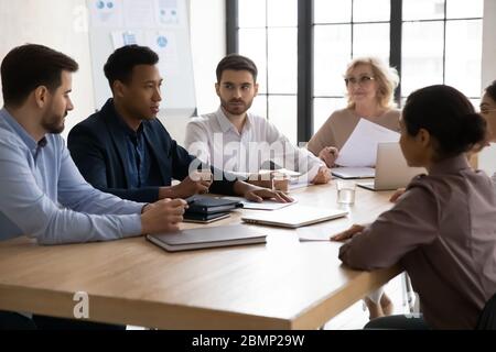Confident african american businessman talking with young and mature colleagues. Stock Photo
