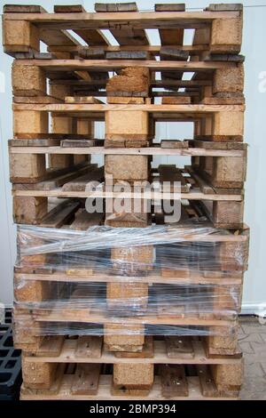 stacked pallets with wooden planks and rusty nails and screws, stored for reuse Stock Photo