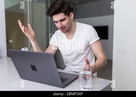 Young man is browsing at his laptop and calling with customer on the sofa at home, Business success Stock Photo