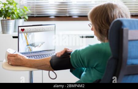 tele health concept senior woman with laptop taking her blood pressure Stock Photo