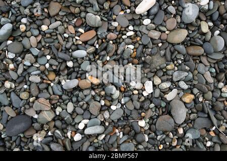 Abstract background texture of random coloured and small sized smooth wet beach pebbles Stock Photo