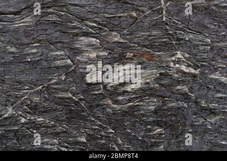 Abstract background of rough textured dark rock surface with white lines and inlay Stock Photo