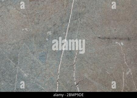 Abstract background of smooth figured grey brown rock surface with thin white fissures Stock Photo