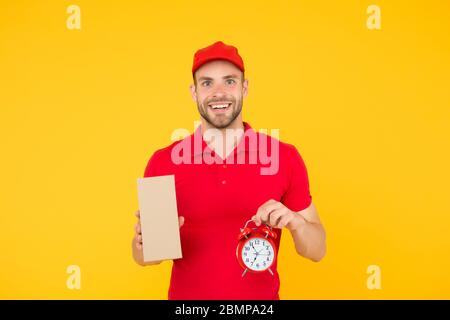delivery time. Delivery Courier with time clock holding box. take your parcel. gift delivery man holding vintage clock. go online shopping. Delivery during quarantine. friendly staff man. Stock Photo