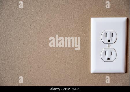 white dual electrical outlet with plate cover on beige colored drywall Stock Photo