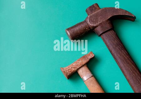 Old rusty hammers on a turquoise background. Two random vintage hammers of different sizes. Craft, manual labor. View from above. Close-up. Stock Photo