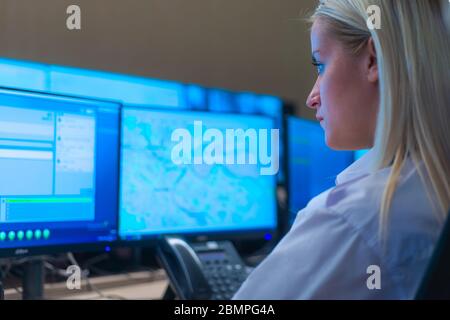 Group of Security data center operators (administrators) working in a group at a CCTV monitoring room while looking at multiple monitors ( computer sc Stock Photo