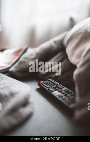 a remote control lying on a sofa between pillows Stock Photo