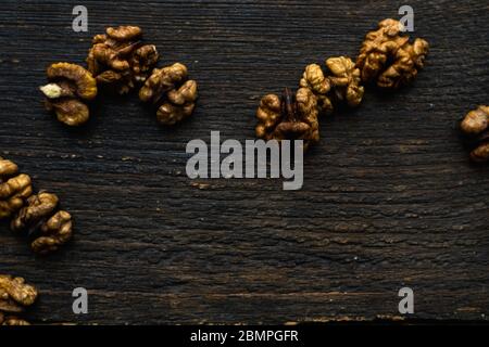Walnut scattered on the wooden vintage table. Copy space. Walnuts is a healthy vegetarian protein nutritious food. Almonds on rustic old wood Stock Photo